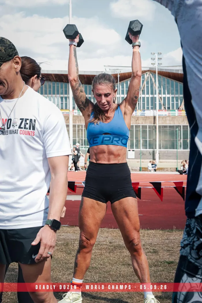 Nina drückt zwei Kurzhanteln über den Kopf bei den Deadly Dozen World Champs